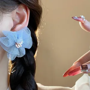 Primo piano di orecchini a fiore in chiffon blu con trame delicate dei petali.