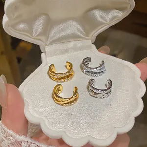 Elegante primer plano de ear cuffs cruzados de tres capas con circonitas en un estuche