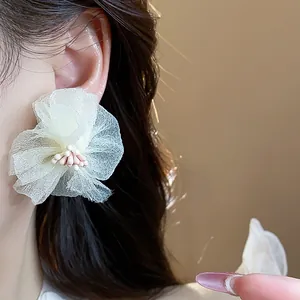 Primo piano della delicata trama di eleganti orecchini a fiore in chiffon bianco