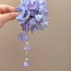 Close-up of purple fabric flower hair clip featuring a delicate pearl tassel design