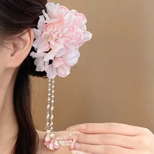 Close-up of sweet pink fabric flower hair clip with pearl tassels worn by a model