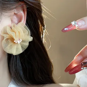 Primo piano dettagliato che mostra eleganti orecchini a fiore in chiffon champagne su una modella