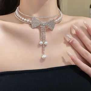 Close-up of elegant rhinestone bow and pearl multi-layer choker on model neckline