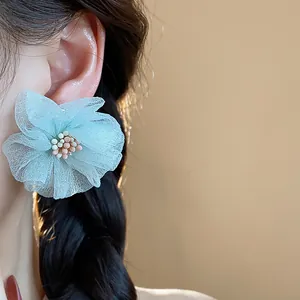 Primo piano di un orecchino a fiore in chiffon azzurro indossato da una splendida modella asiatica