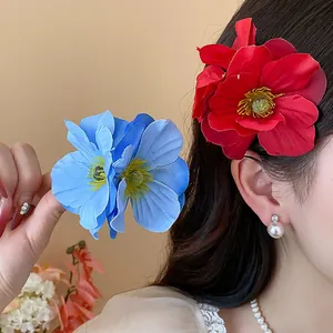 Détail de barrettes à fleurs en tissu rouge et bleu élégantes portées par un mannequin de mode