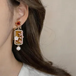 Primo piano di orecchini vintage con ciondolo ambra e goccia di perla bianca elegante.