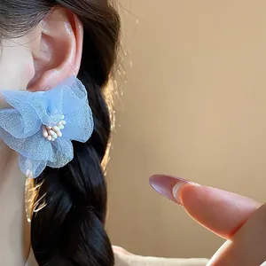 Dettaglio macro di un orecchino a perno a fiore in chiffon blu con petali fini