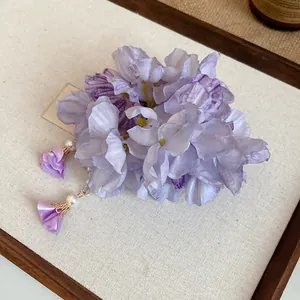 Macro detail of Bohemian purple fabric flower hair clip with delicate pearl tassels