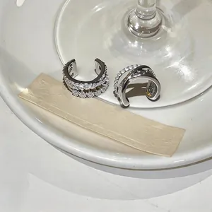 Primer plano de earcuffs plateados con diseño cruzado e incrustación de circonitas