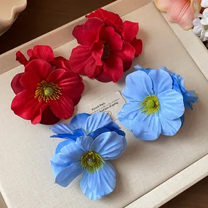 Vue détaillée de pinces à cheveux en forme de fleurs en tissu rouge et bleu sur un plateau