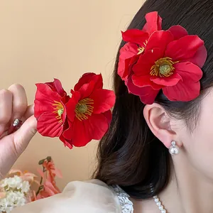 Vue détaillée d'une pince à cheveux en fleur de tissu rouge avec étamines jaunes portée