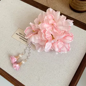 Close-up detail of pink fabric flower hair clip with elegant dangling pearl tassels.