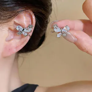 Close-up detail of a silver zircon butterfly and flower ear cuff worn on the ear