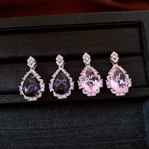 Vista dettagliata di orecchini a goccia in zirconia viola e rosa in una scatola