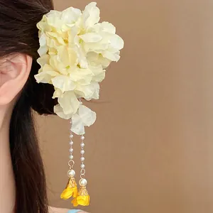 Detailed view of a bohemian fabric flower hair clip with elegant pearl tassels on hair