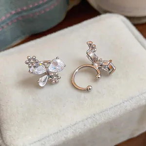 Close-up detail of silver butterfly ear cuffs with zircon flowers on a beige velvet box