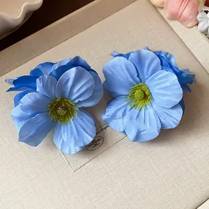 Vue détaillée de pinces à cheveux élégantes avec fleurs en tissu bleu sur un plateau