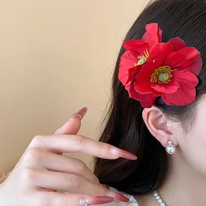 Détail d'une pince à cheveux élégante en fleur de tissu rouge pour un style de vacances chic