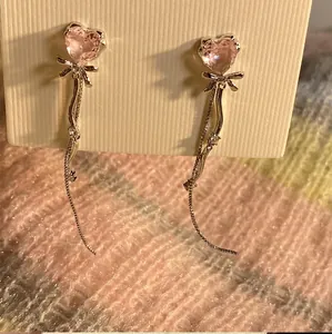Detailed view of pink heart zircon earrings with bow knots and long silver tassels