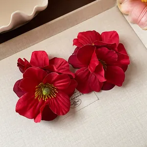 Gros plan détaillé de pinces à cheveux fleurs en tissu rouge au design plissé