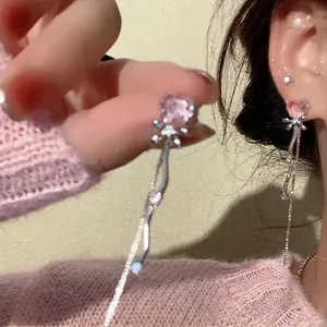 Detail showing elegant pink heart crystal earrings with bow and long tassels