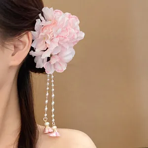 Detailed side view of ethereal pink fabric flower hair clip with dangling pearl tassels