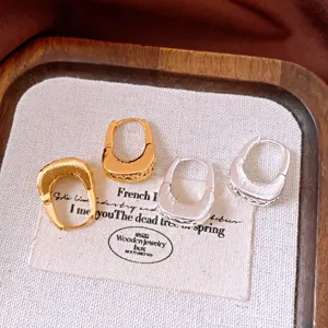 Dettaglio di orecchini a cerchio a U placcati oro 18 carati con texture a pieghe
