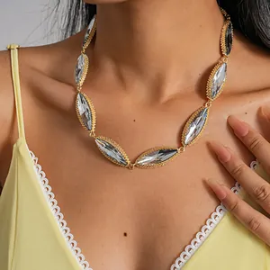 Macro view of an elegant gold marquise crystal statement necklace on a female model.