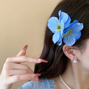 Détail d'une pince à cheveux en fleur de tissu bleu sur cheveux sombres, style éthéré.