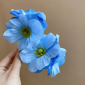 Gros plan d'élégantes pinces à cheveux en fleurs de tissu bleu avec étamines jaunes.