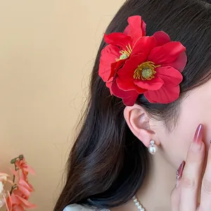 Vue détaillée d'une élégante pince à cheveux fleur en tissu rouge sur cheveux bruns