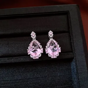 Dettaglio macro di orecchini a goccia in zircone rosa scintillante in custodia