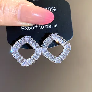 Gros plan sur des boucles d'oreilles carrées évidées de style vintage avec zircons