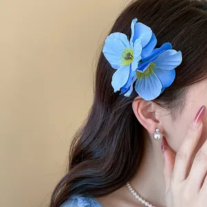 Détail d'une élégante pince à cheveux fleur en tissu bleu sur cheveux bruns ondulés