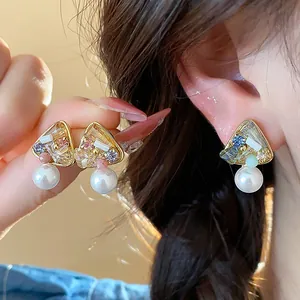 Detailed view of geometric pearl earrings with colorful crystals and gold plating