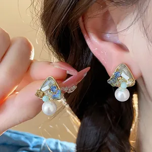 Close-up detail of stylish 18k gold plated geometric pearl drop earrings on ear