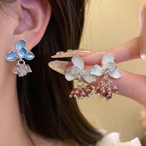 Close-up detail of elegant floral enamel earrings with pearls and crystal accents.