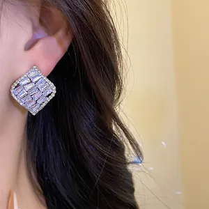 Gros plan de boucles d'oreilles carrées en zircone de style vintage portées à l'oreille
