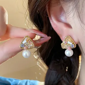 Detailed view of 18k gold plated triangle stud earrings with pearl and colorful crystals