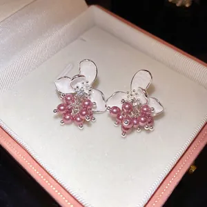 Detailed view of elegant floral stud earrings with pink pearls inside a pink gift box