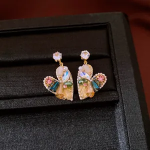 Detail of heart-shaped drop earrings with colorful gemstones and pearls in a black box