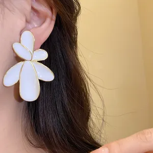 Elegant oversized white enamel flower stud earrings with gold trim on model ear