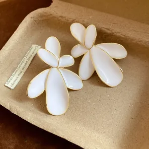 Detailed close-up of elegant white flower petal earrings with vintage gold edges