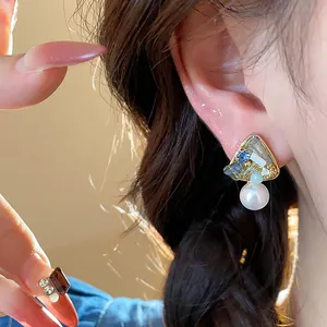 Detailed view of elegant geometric pearl earrings with 18k gold plating and blue resin