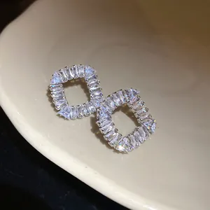 Détail macro montrant l'éclat brillant des zircons sur des boucles d'oreilles carrées évidées
