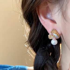 Close-up view of a luxury 18k gold-plated geometric earring with pearl and stones