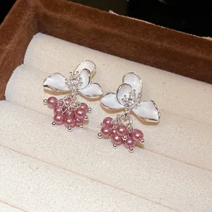 Detailed close-up view of elegant white enamel flower stud earrings with purple pearl charms