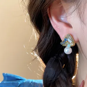 Close-up view of elegant geometric 18k gold plated pearl stud earrings on ear