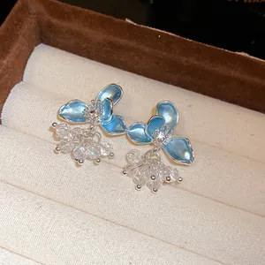 Detailed close-up of light blue enamel flower earrings with clear crystal bead clusters.