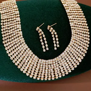 Detail view of a luxury gold-toned necklace and tassel earring set with clear rhinestones.